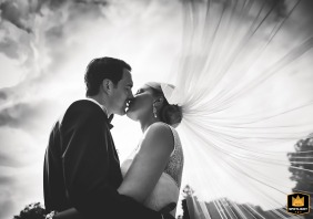 Black and White Wedding Portrait in Moenchengladbach, Germany This stunning black and white wedding portrait captures the romantic kiss between a groom and bride. They are outdoors in Moenchengladbach, Germany, posed face to face and sharing a loving kiss. The bride's veil is gracefully flowing in the sky.